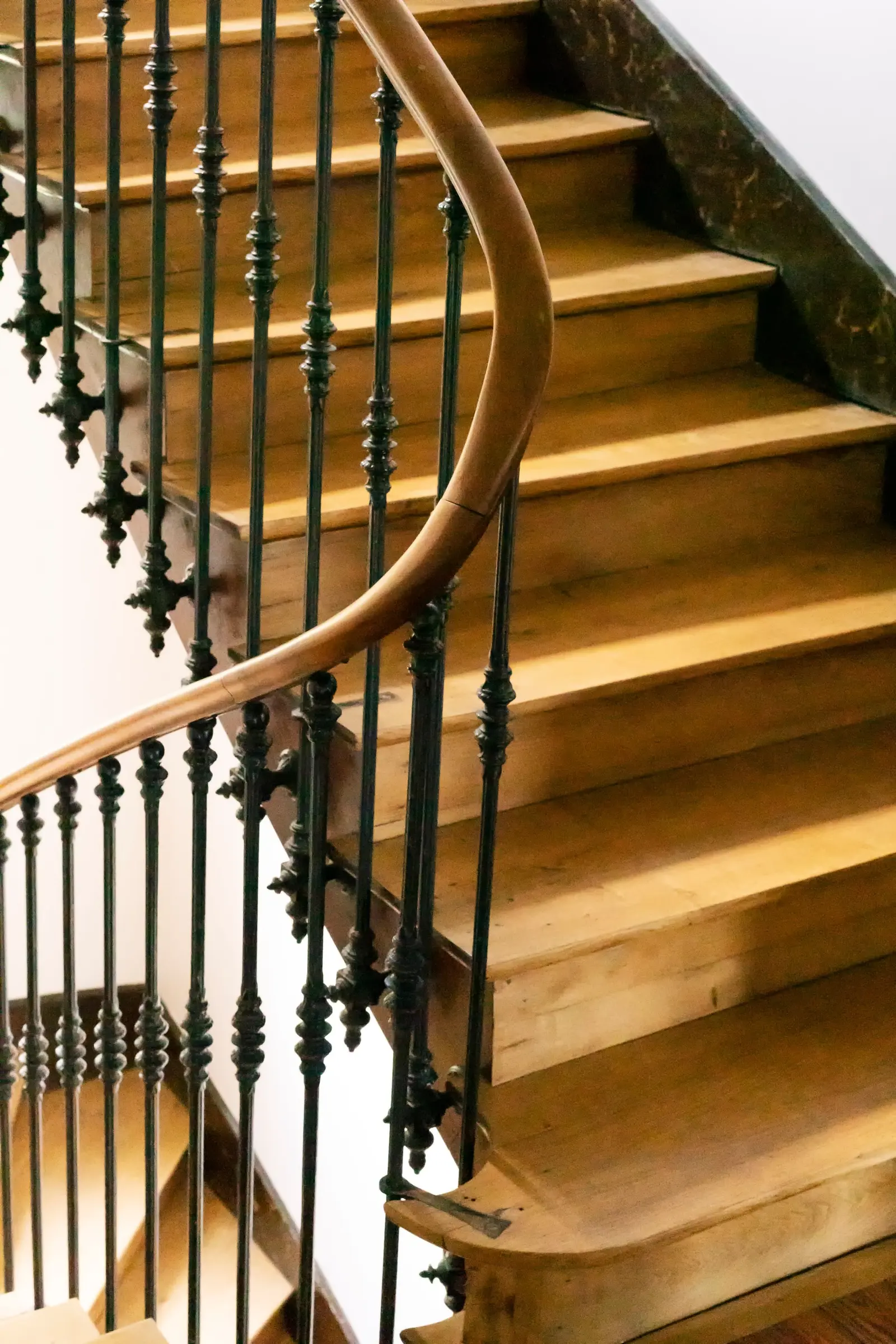 Drewniane schody w starym domu z kutą balustradą i drewnianą poręczą